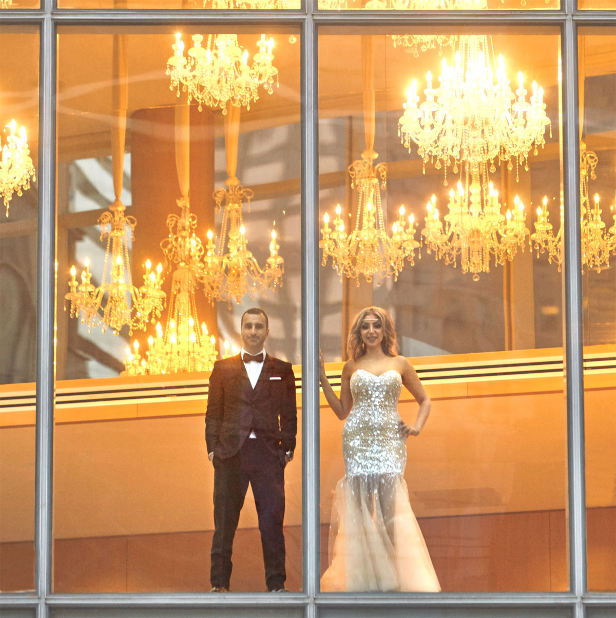 Couple behind glass beneath chandeliers