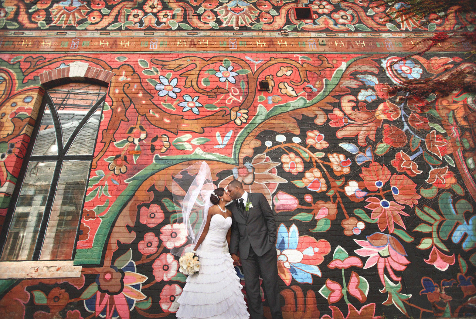 Couple kissing before a painted floral mural