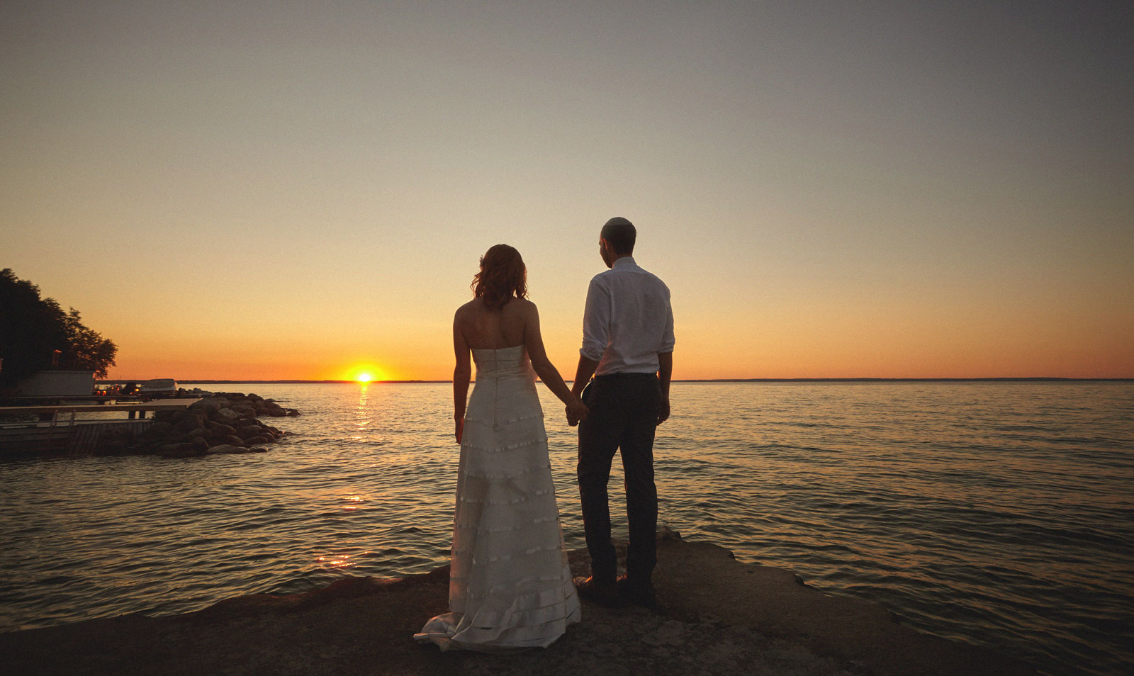 Couple silhouetted at sunset by the water